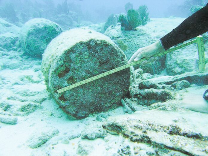 a person measuring a piece of metal in the ocean