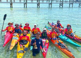 a group of people standing in the water with kayaks