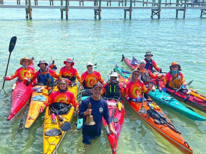 a group of people standing in the water with kayaks