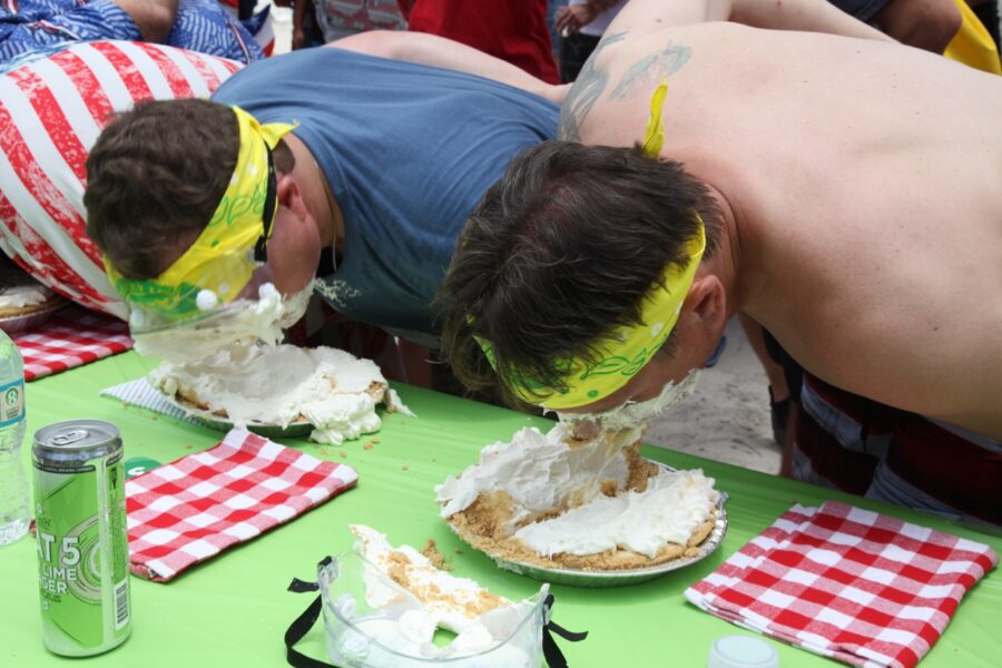 a couple of men are eating cake on a table