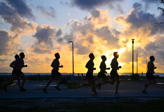 a group of people running down a street at sunset
