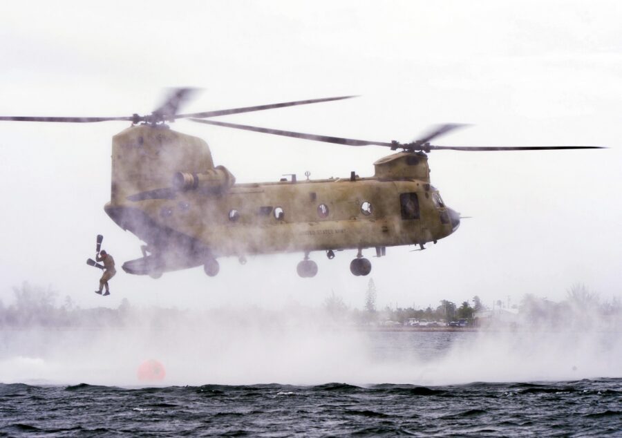 a military helicopter flying over a body of water