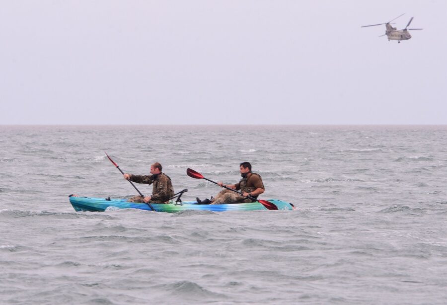 two people in a kayak with a helicopter in the background
