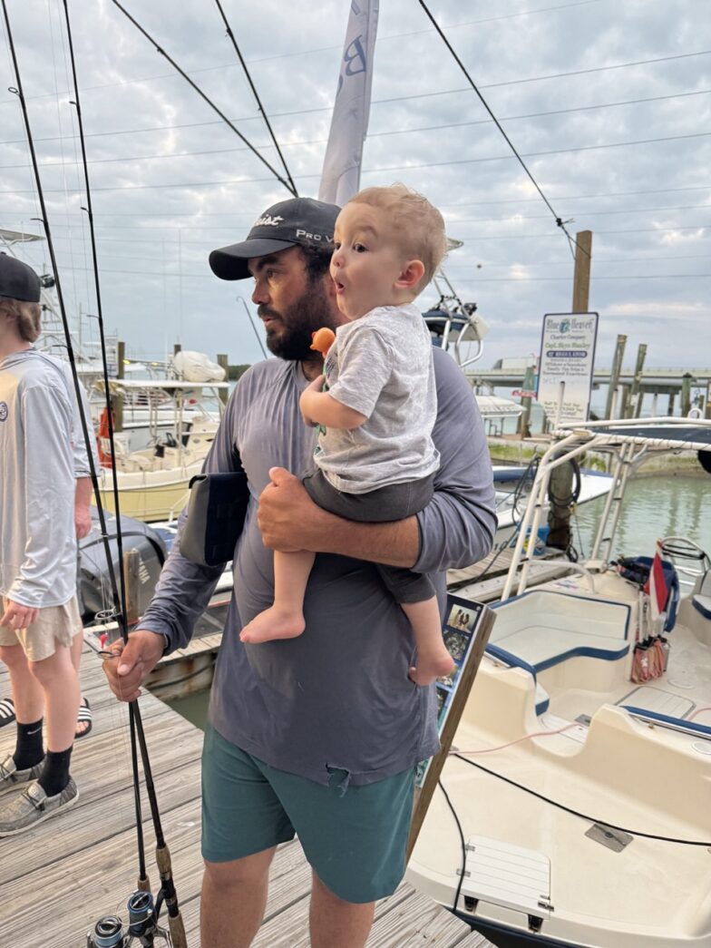 a man holding a child while standing on a dock