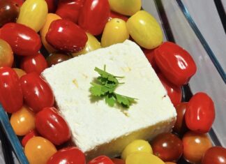 a square piece of cheese surrounded by tomatoes and other fruits