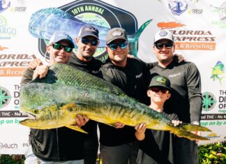 a group of men standing next to each other holding a fish