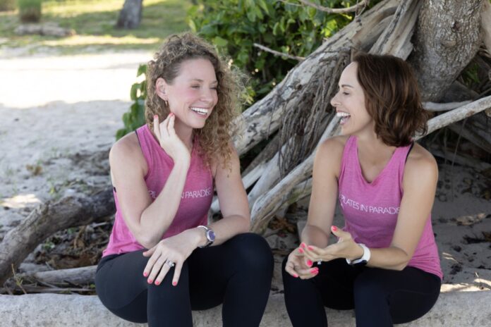 two women sitting on a rock talking and laughing