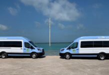 two blue and white vans parked in front of the ocean