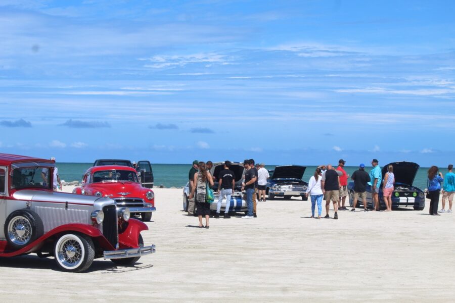 a group of cars parked on top of a sandy beach