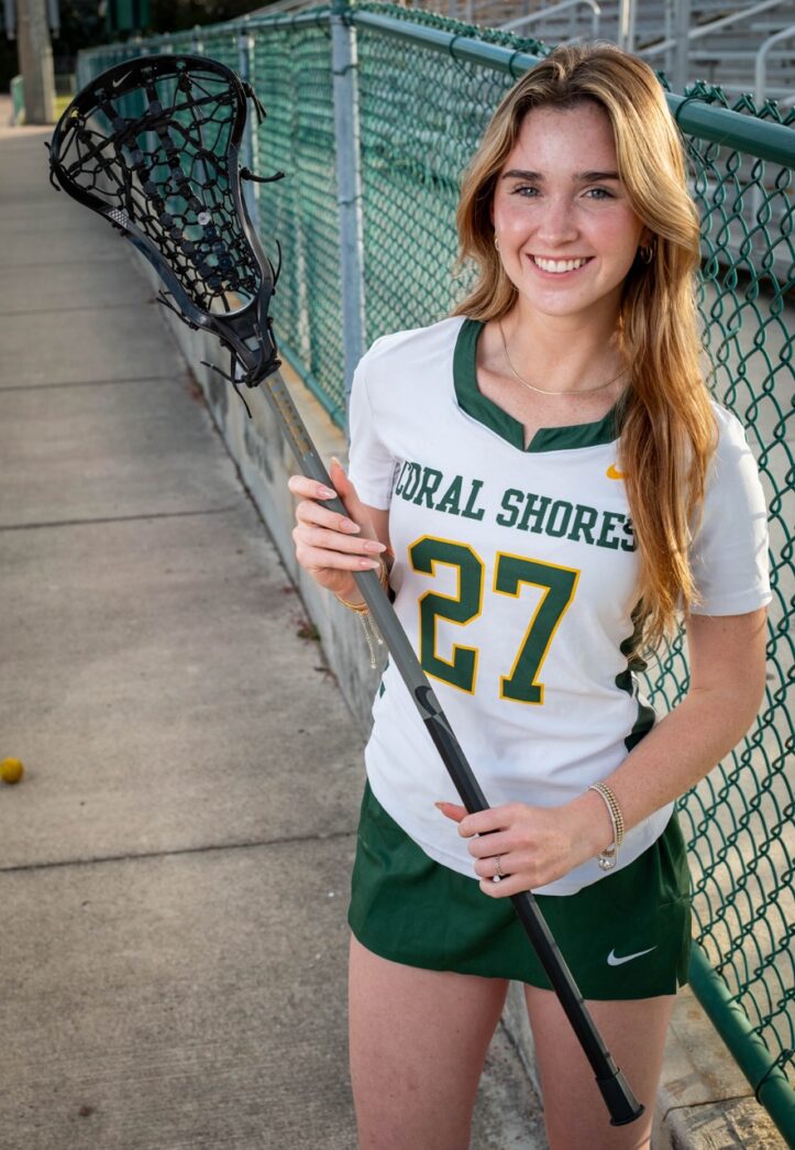 a girl in a green and white uniform holding a lacrosse stick