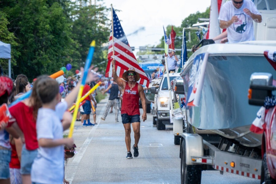 a group of people walking down a street holding american flags