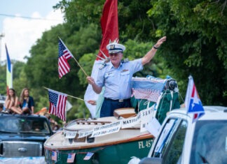 a man waving from a boat in a parade