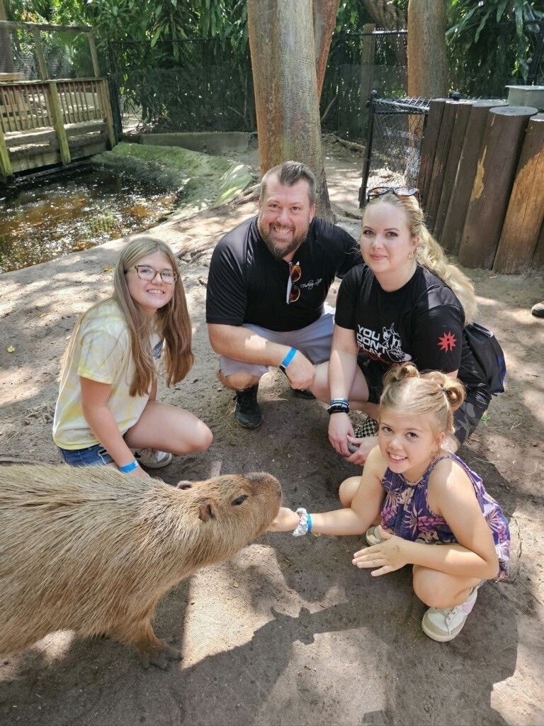 a group of people petting a capy animal