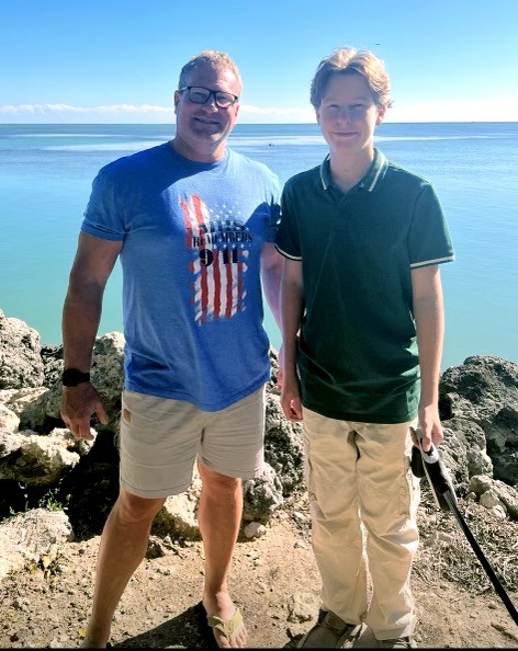a couple of men standing next to each other near the ocean