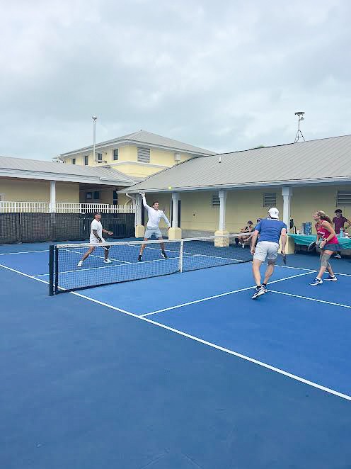 a group of people playing tennis on a blue court