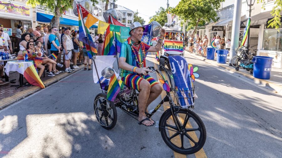 a man riding a bike down a street next to a crowd of people