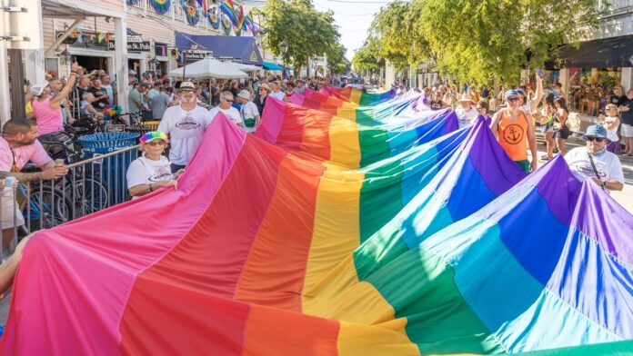 a group of people walking down a street holding a rainbow flag