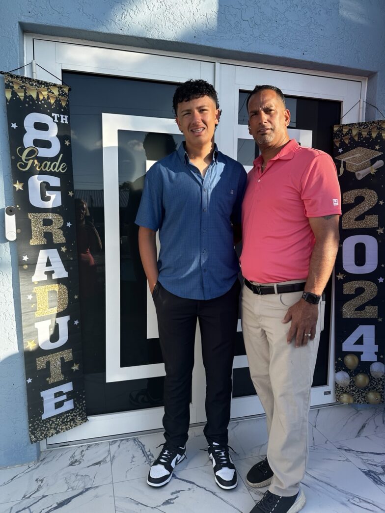 two men standing next to each other in front of a building