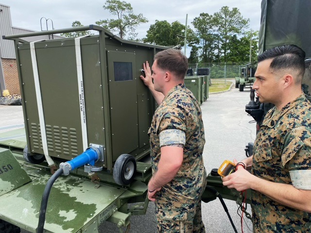 a couple of men standing next to a green truck