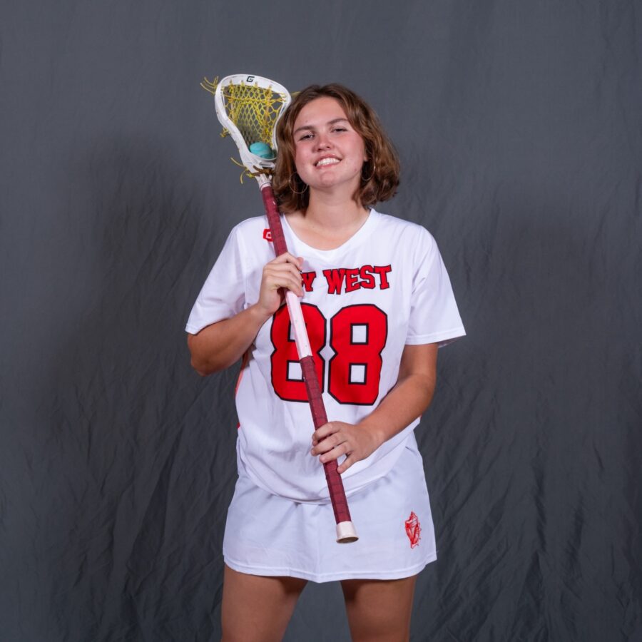 a girl in a white jersey holding a lacrosse racket