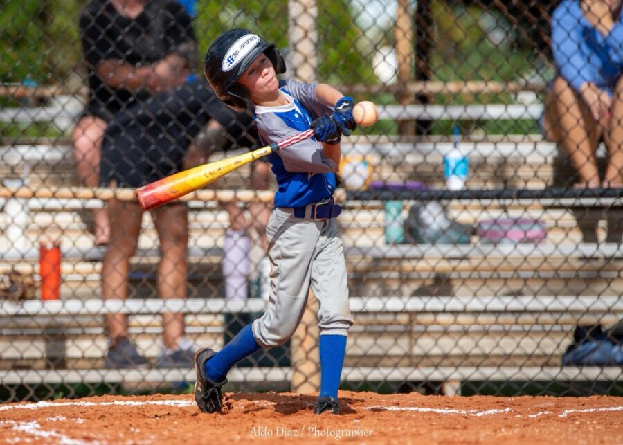 a young boy swinging a baseball bat at a ball
