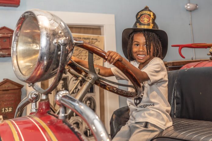 a young boy in a hat sitting on top of a car