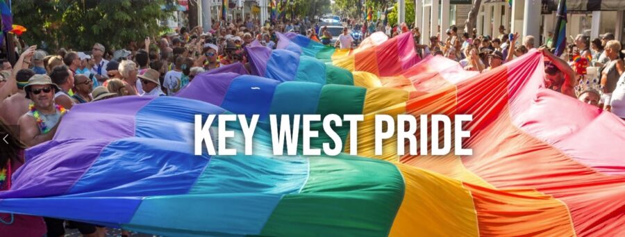 a crowd of people walking down a street with a rainbow colored umbrella