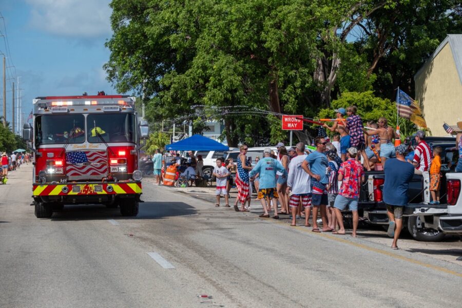 a fire truck driving down a street next to a crowd of people
