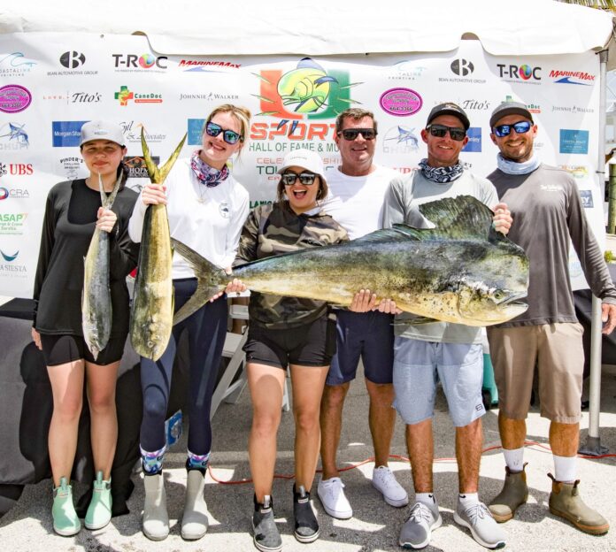 a group of people standing next to each other holding fish