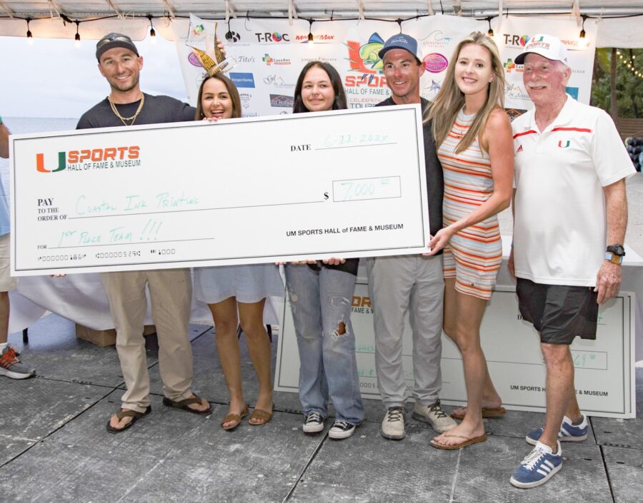 a group of people standing next to each other holding a large check