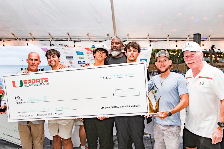 a group of men standing next to each other holding a large check