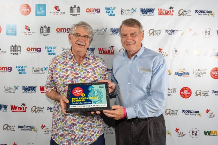 two men standing next to each other holding an award