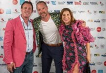 two men and a woman standing on a red carpet