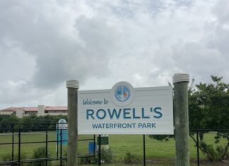 a sign for rowell's waterfront park on a cloudy day