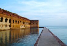 a long brick wall next to a body of water