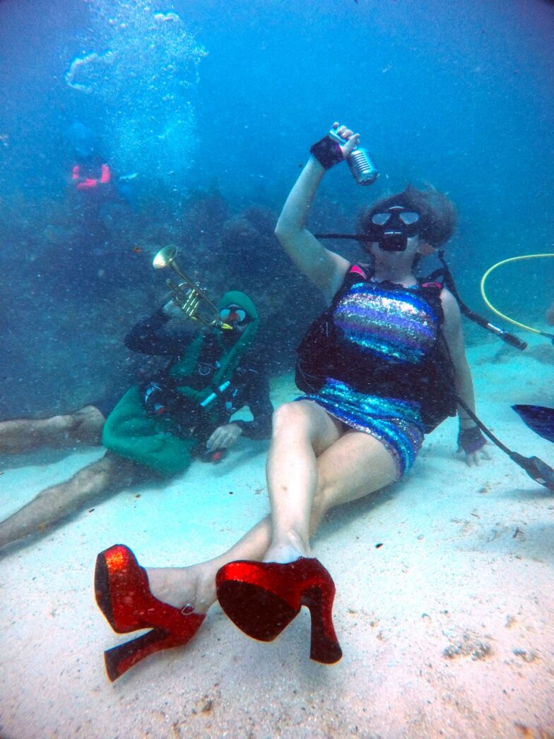 a woman sitting on the bottom of a sandy ocean floor