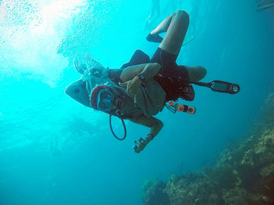 a woman scubas in the ocean with a camera