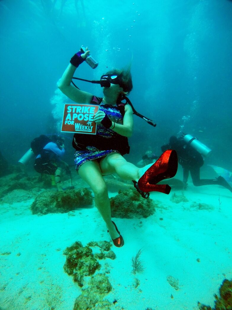 a woman scubas in the ocean holding a sign