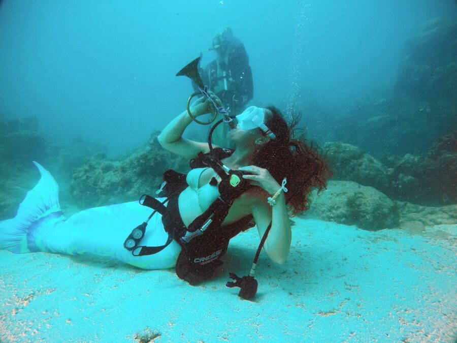 a woman with a camera taking a picture of a mermaid