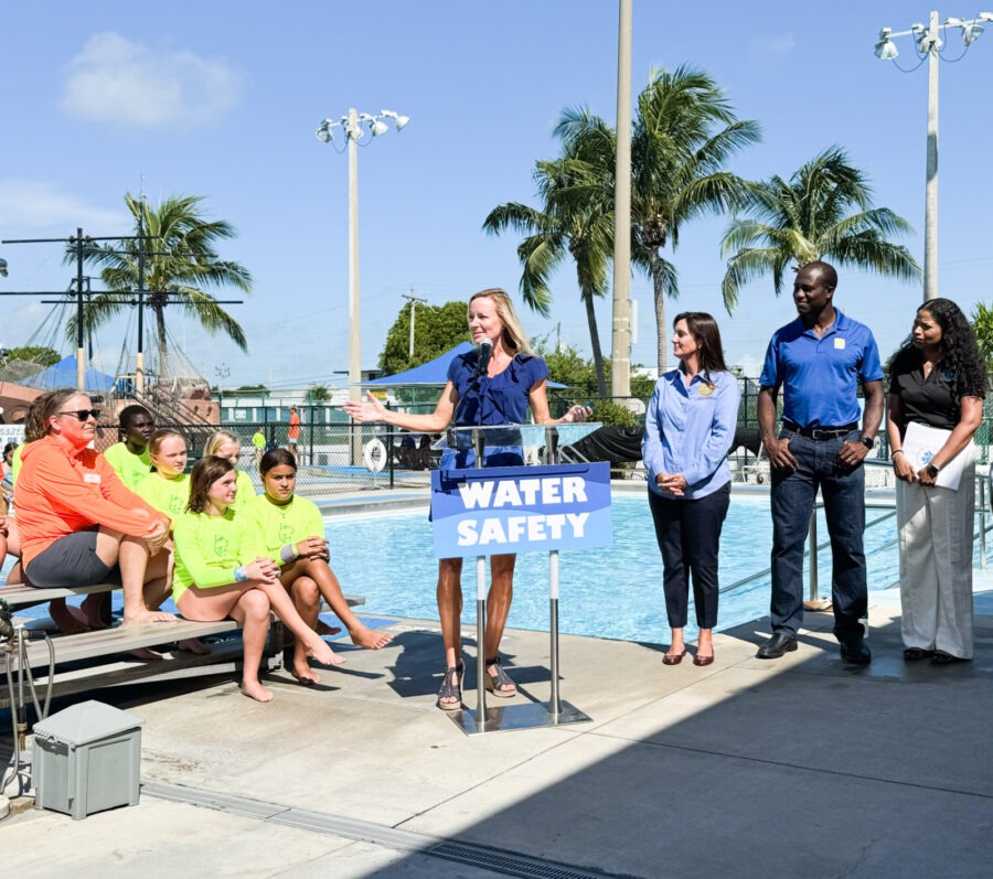 a group of people standing next to a swimming pool