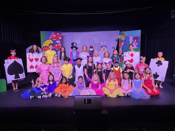 a group of children sitting on top of a stage