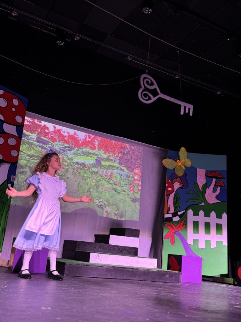 a little girl standing on a stage in front of a projector screen