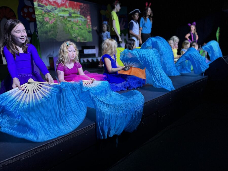 a group of young girls sitting on top of a stage