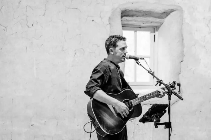 a man playing a guitar and singing into a microphone