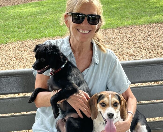 a woman sitting on a bench with two dogs