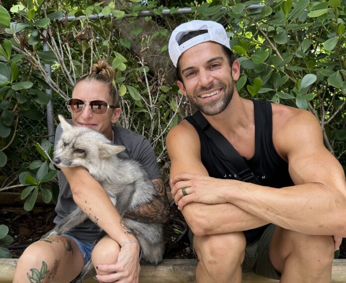 a man and a woman sitting on a log with a cat