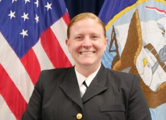 a woman in uniform standing in front of flags