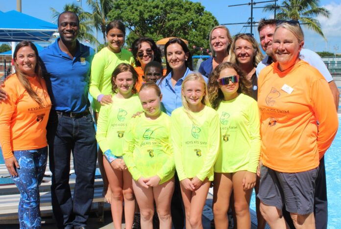 a group of people standing next to a swimming pool