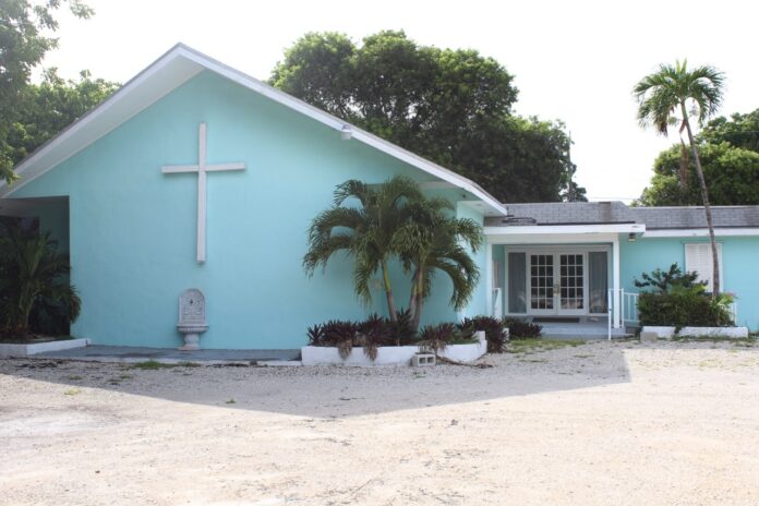 a blue church with palm trees in front of it