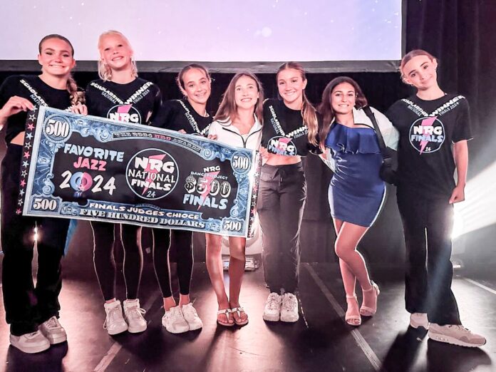 a group of people standing on a stage holding a large check